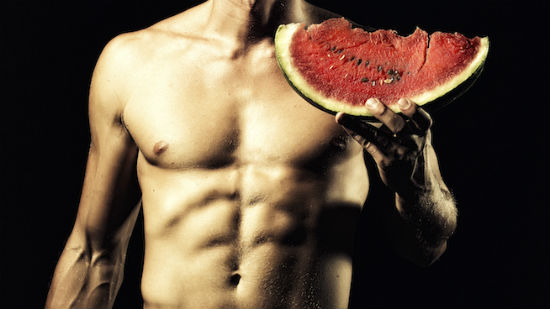 Muscular man holding watermelon